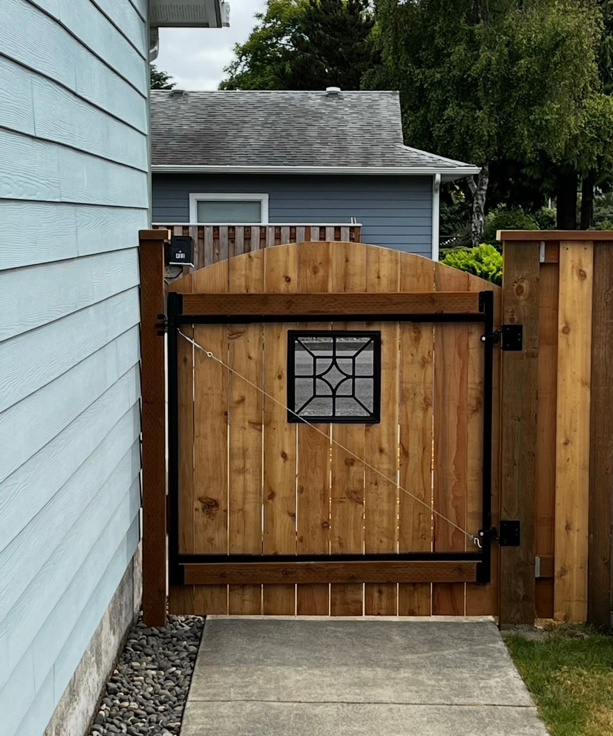 Custom cedar fence with arched gate and stained-glass window insert